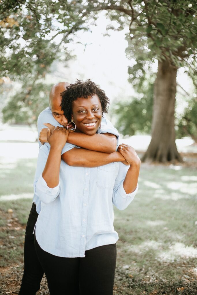 Black man hugging a smiling Black woman from behind