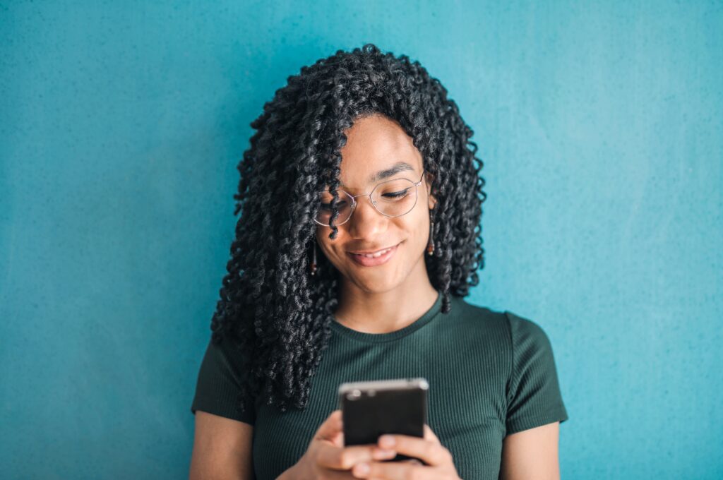 Black woman smiling as she looks at her cell phone