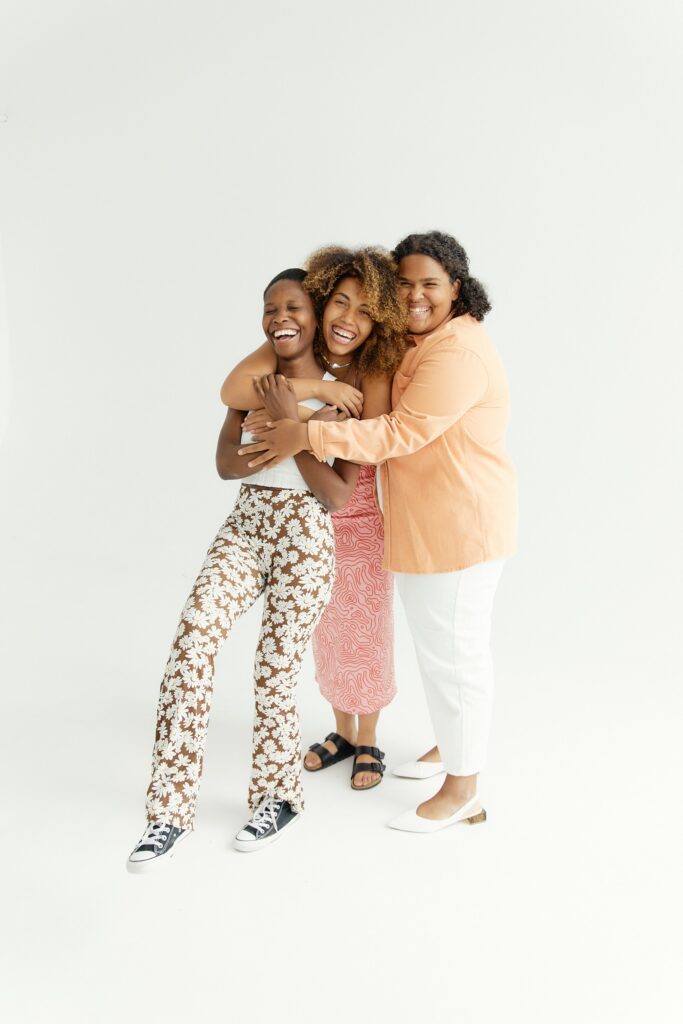 Three Black female friends hugging each other while smiling