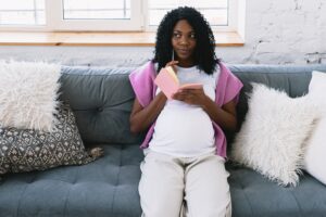 Pregnant Black woman thinking with a pen and pad in her hands