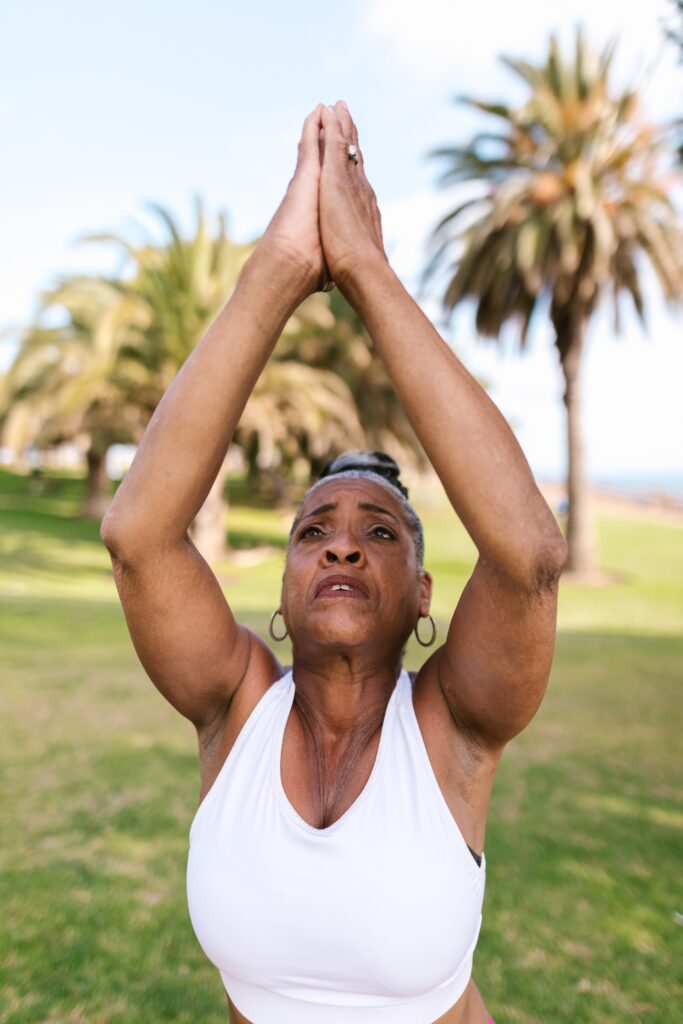 Older Black women doing a yoga pose at a park