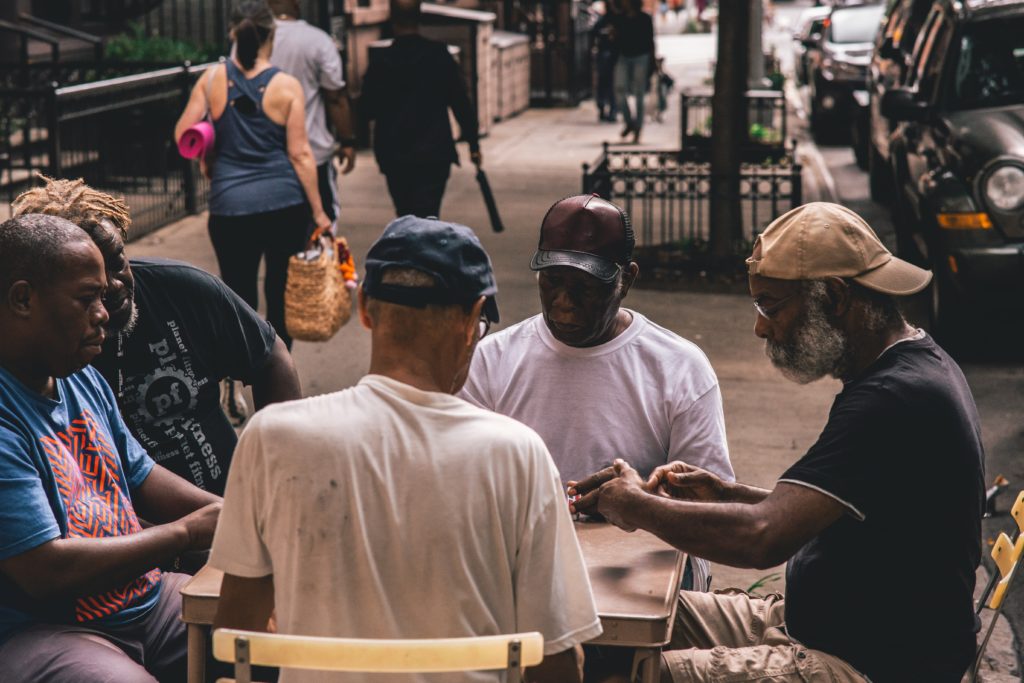 A group of Black men playing cards at a table outside