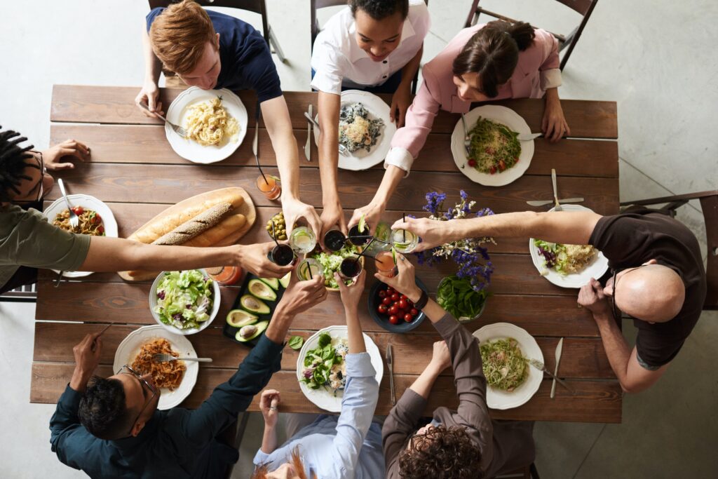 A group of people clinking glasses over a meal.