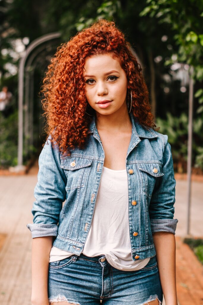 Mixed race woman with curly red hair looking into the camera