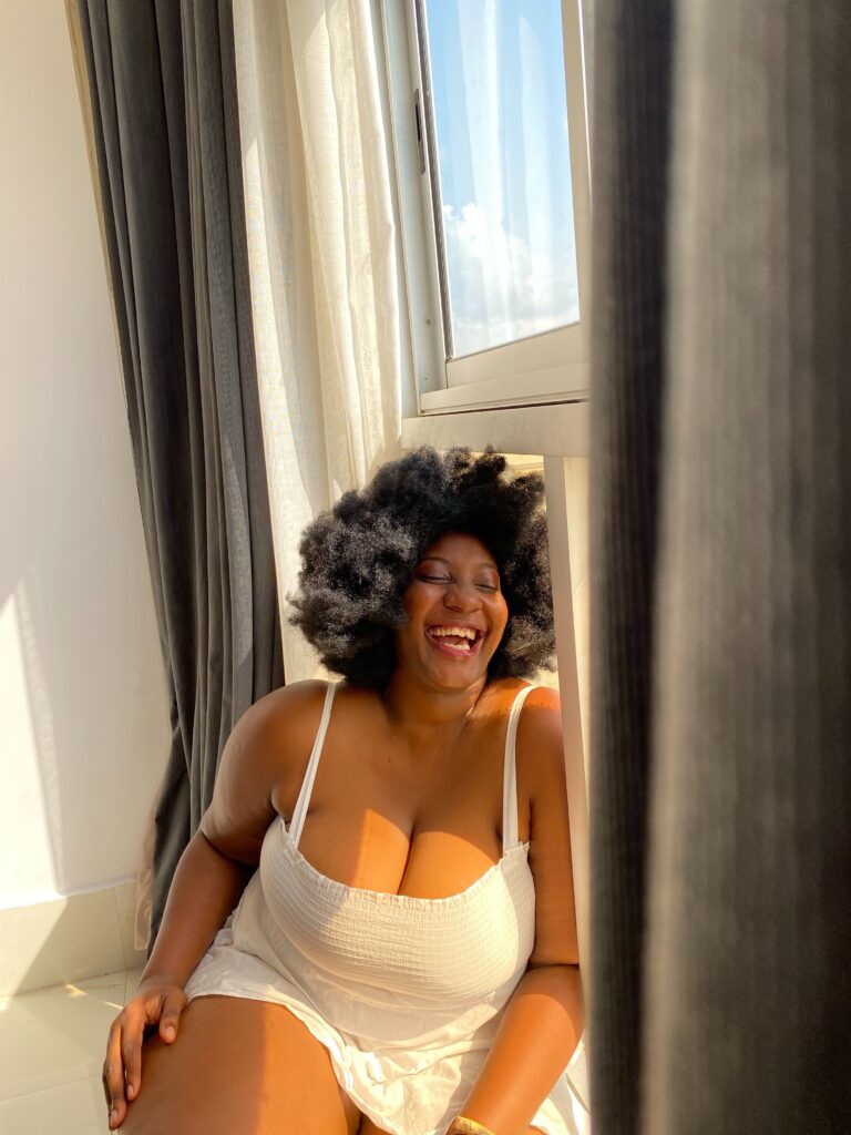 Plus size Black woman laughing into the camera.