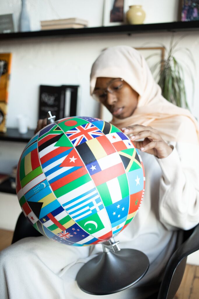 Black woman studying a globe decorated with different country flags