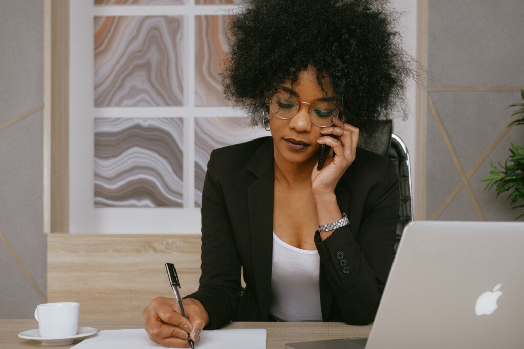 Busy Black woman writing in front of her laptop