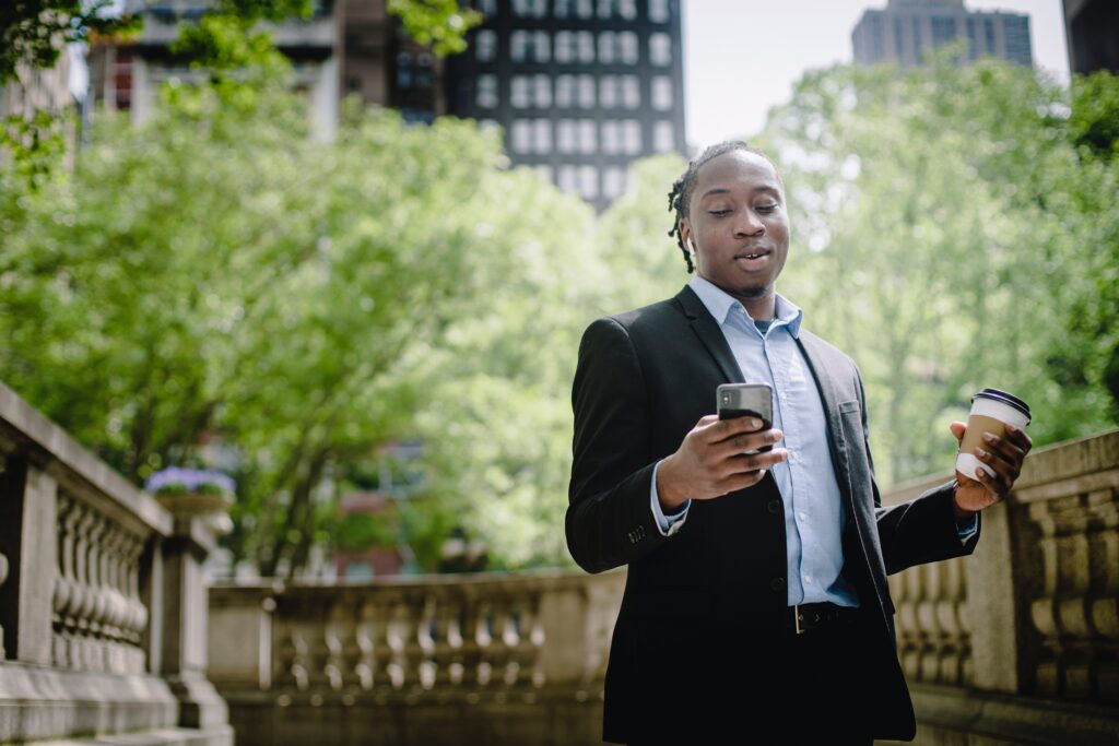 Black man in a business suit looking down at his cellphone
