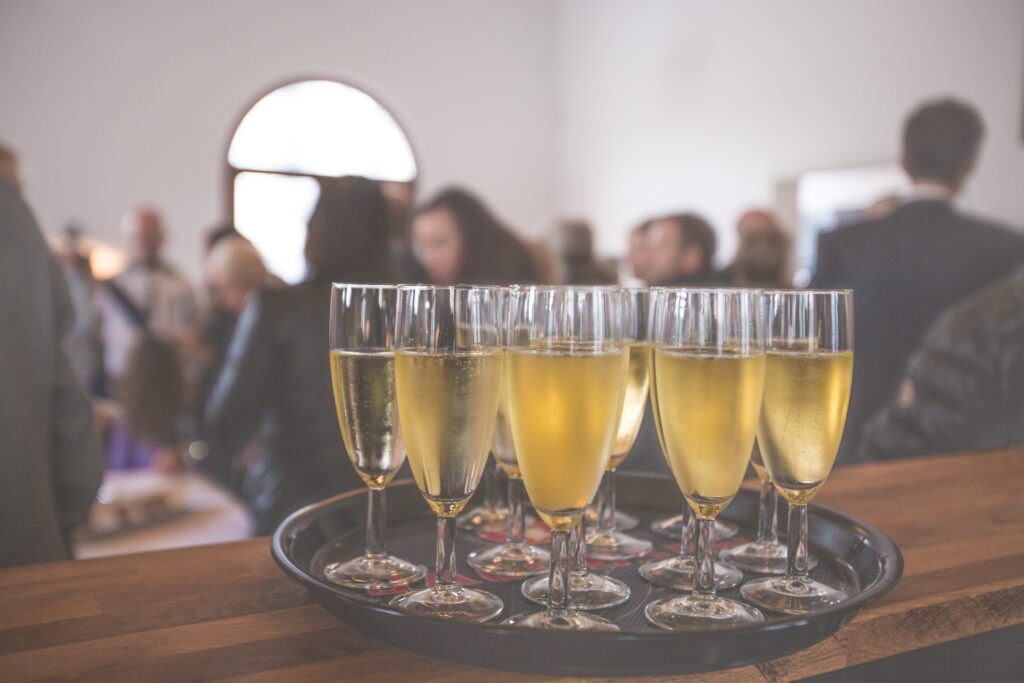 A tray of champagne flutes sitting in front of a group of people.