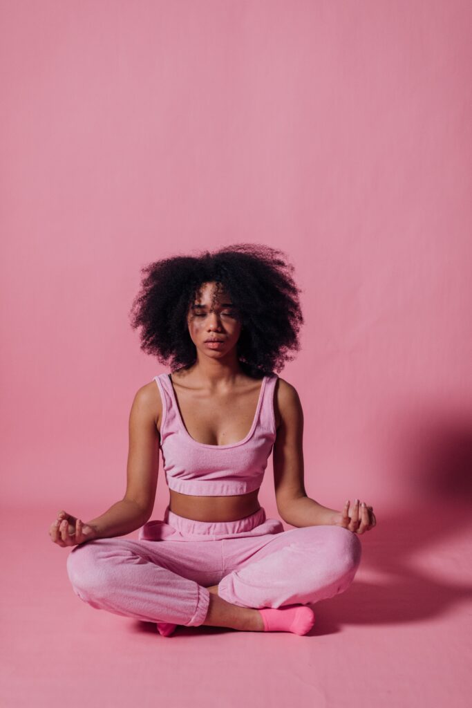 Black woman meditating in all pink against a pink background