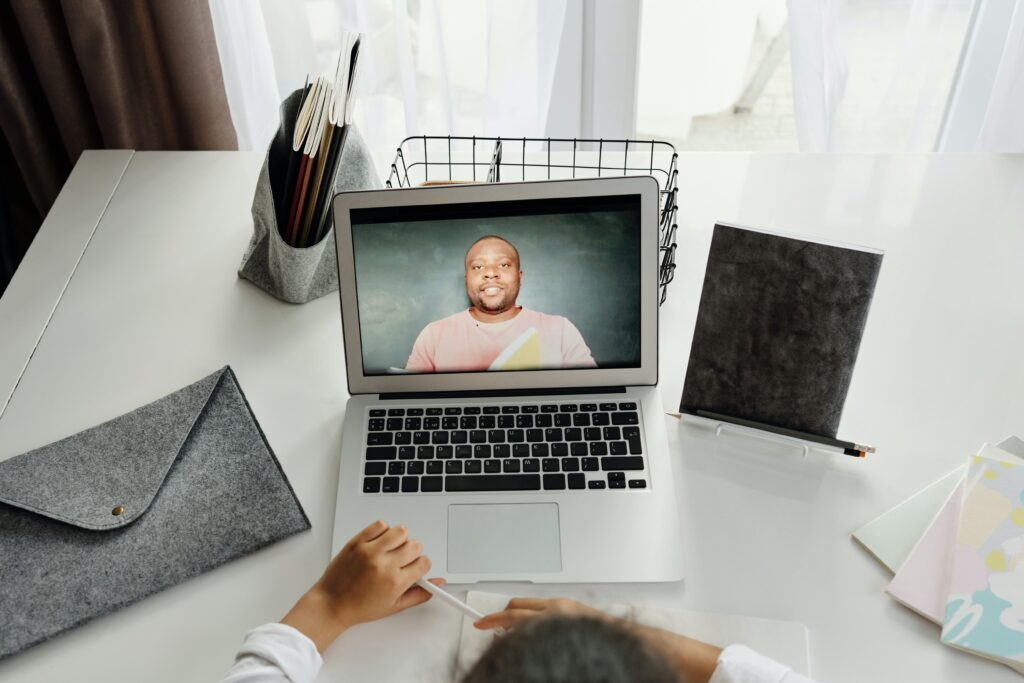 A picture of a laptop showing a Black man speaking on a video call.