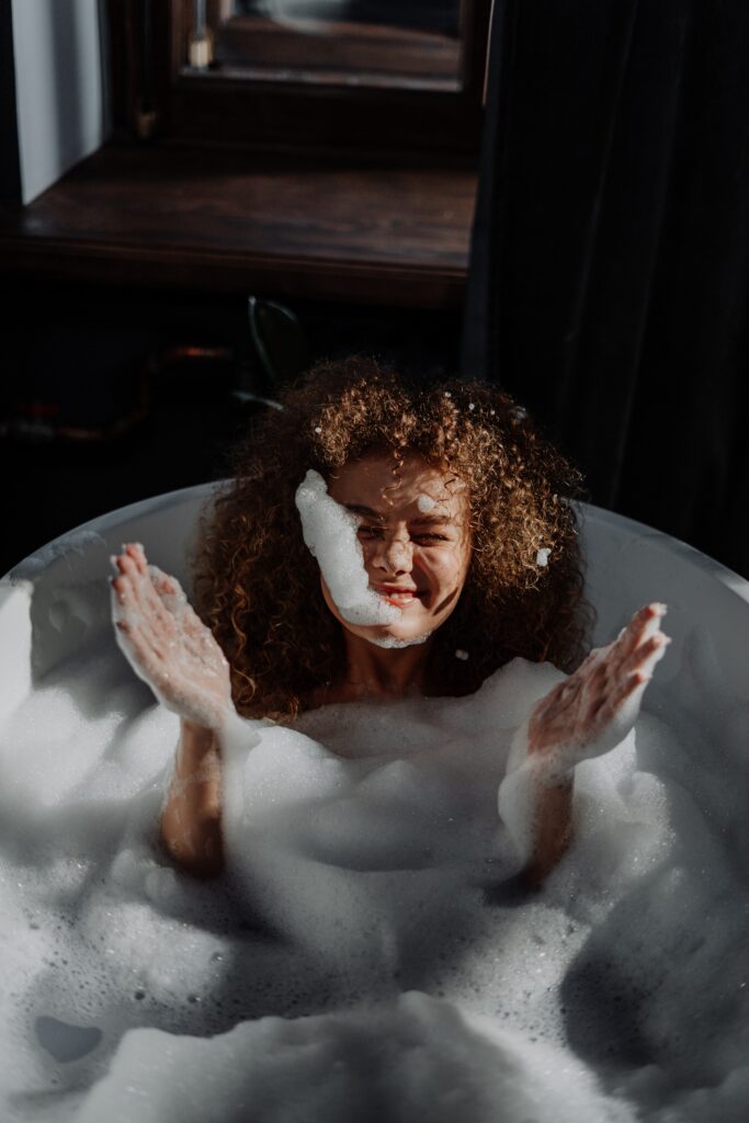 Woman in a bubble bath with soap on her face
