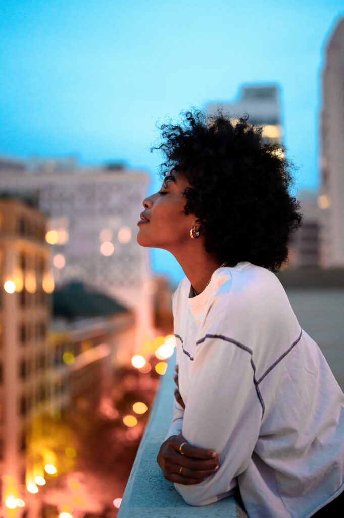 Black woman on a rooftop smiling with her eyes closed