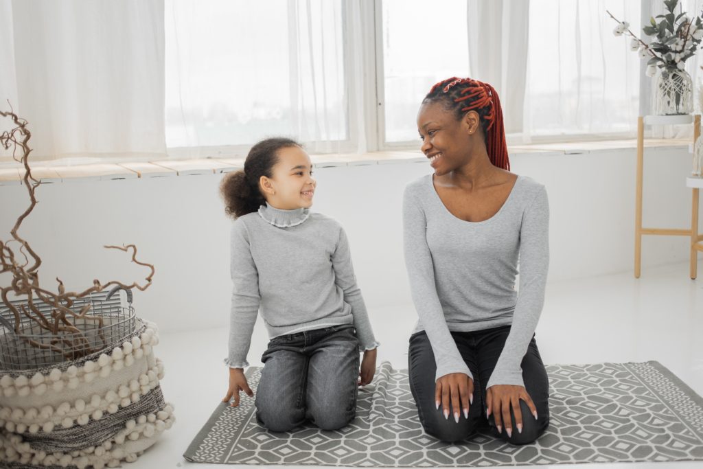 Black mother and daughter kneeling on the floor together