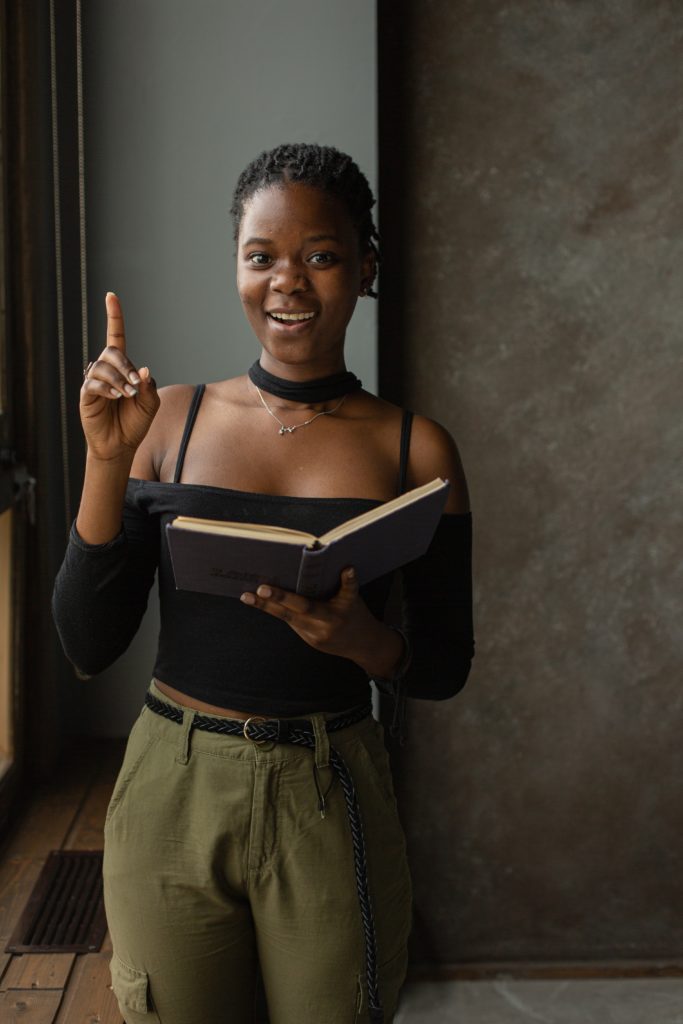 Smiling Black girl holding a book as part of an improv hobby performance