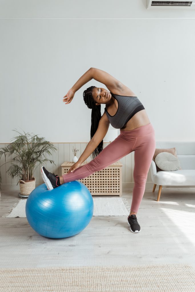 Black woman stretching with an exercise ball for weight loss