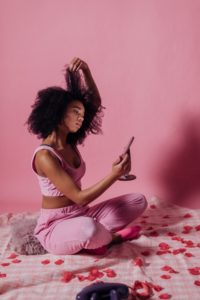 Black woman tugging on her hair while looking in the mirror