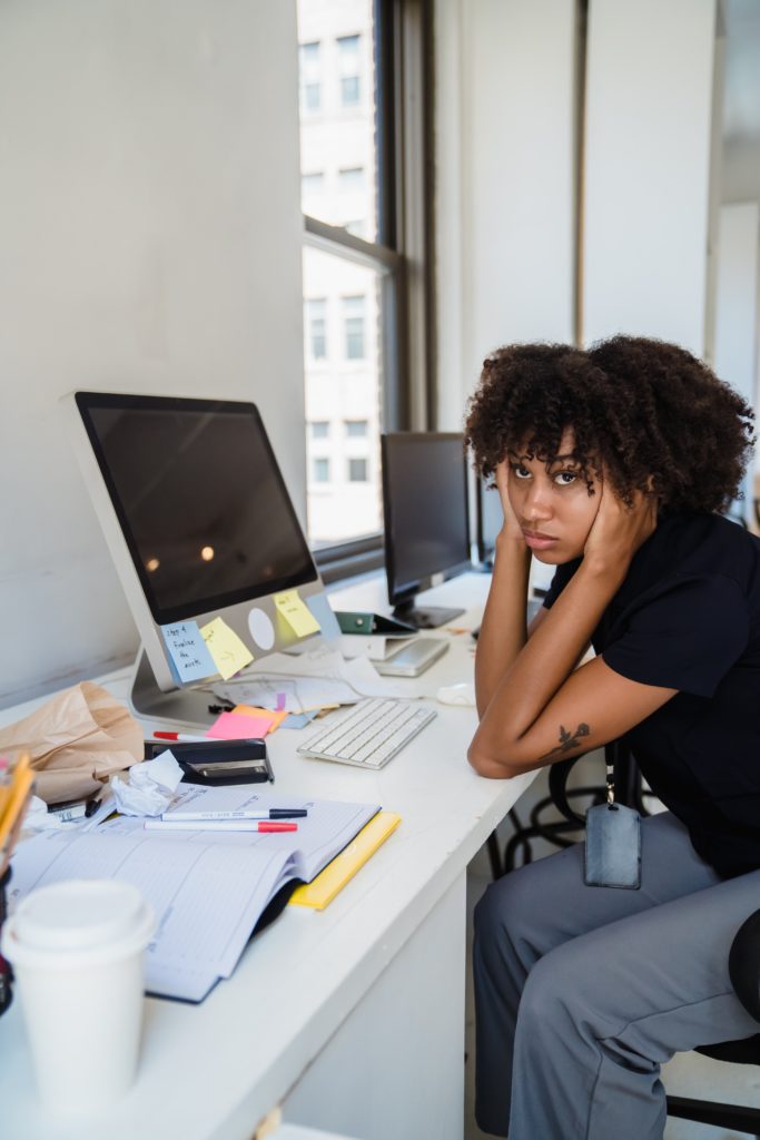 Stressed out woman with her head in her hands at her desk