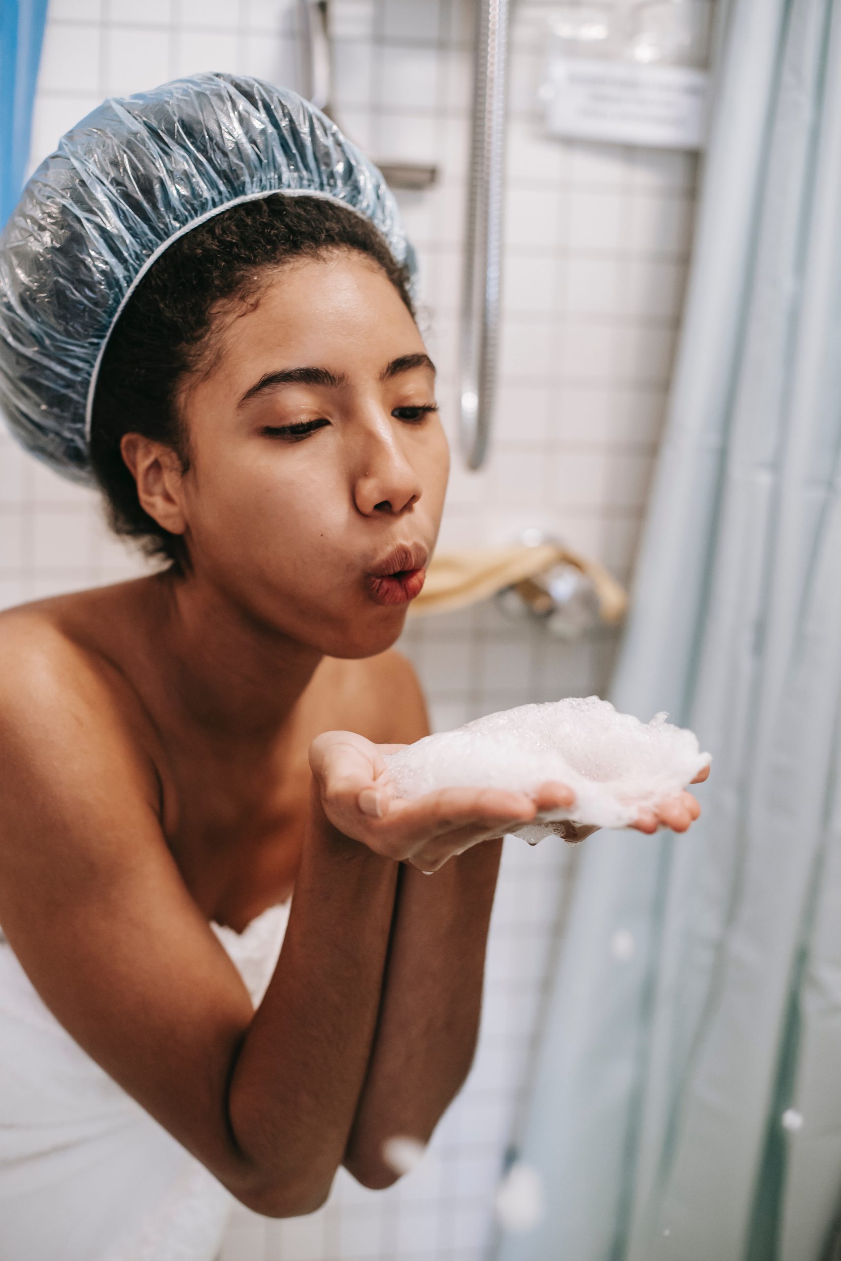 Black girl blowing soap suds from her hands 