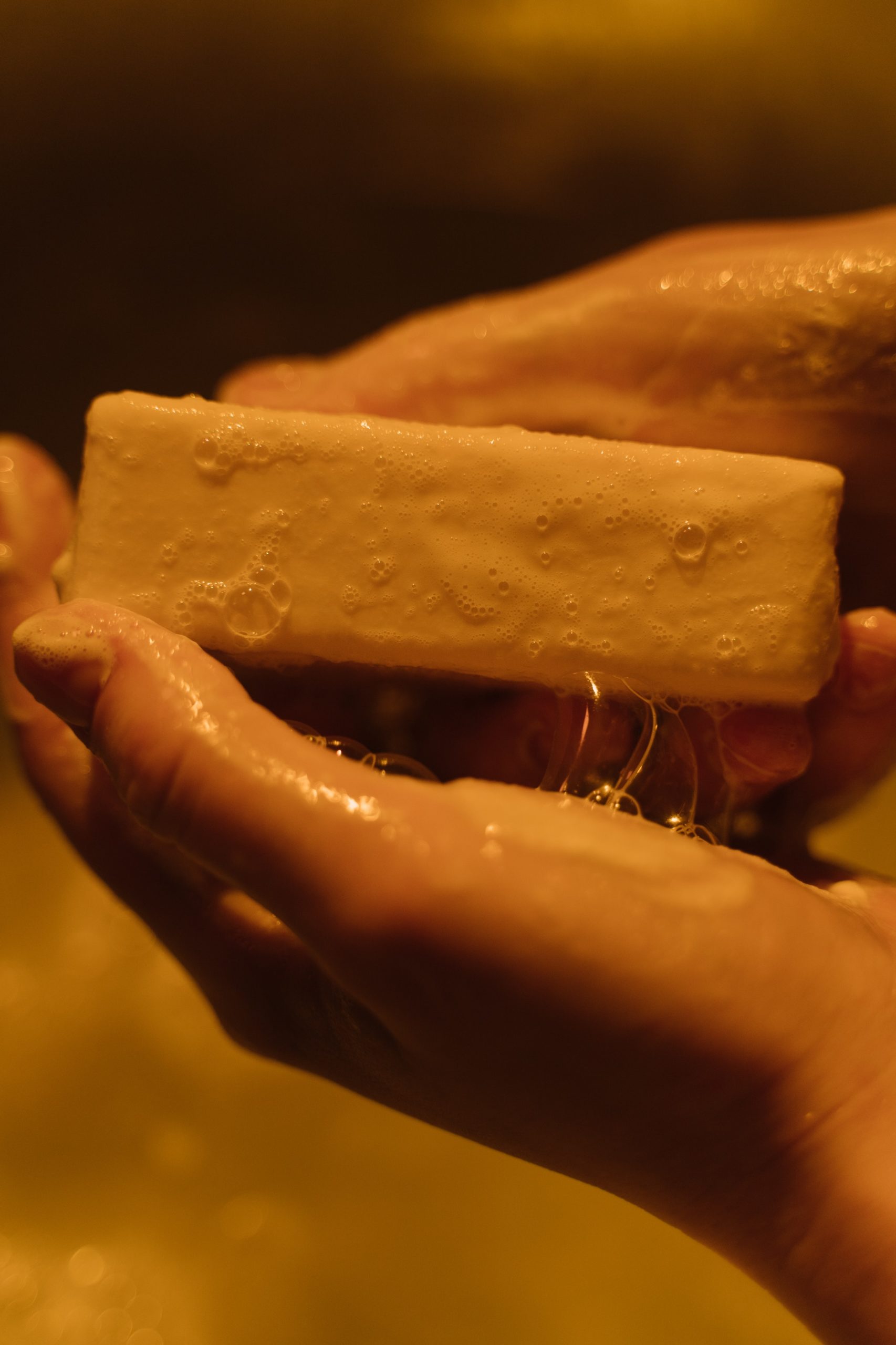 A closeup of hands holding a wet bar of soap