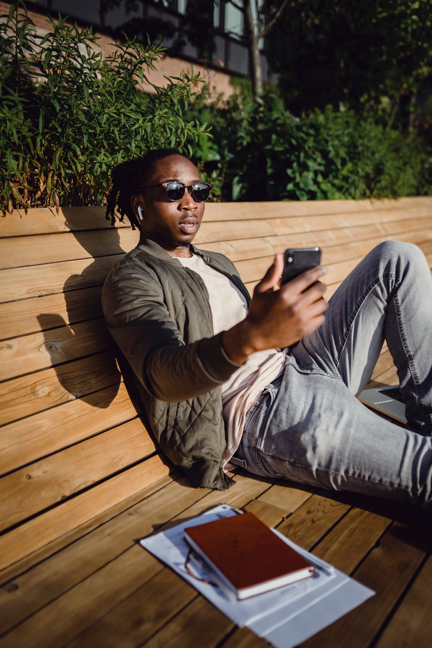 A Black man sitting on a bench looking at his phone