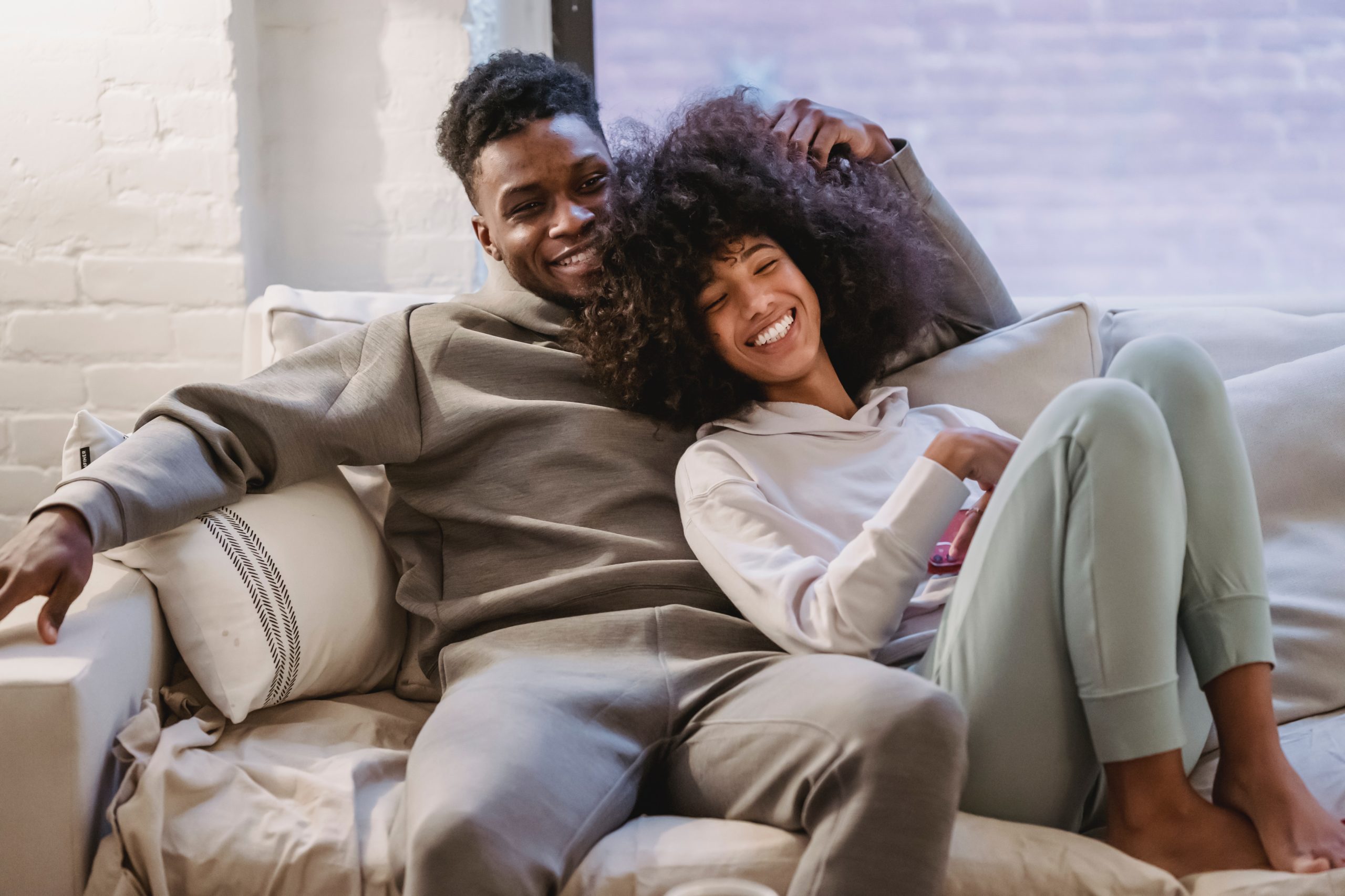 A Black couple laughing on the couch together