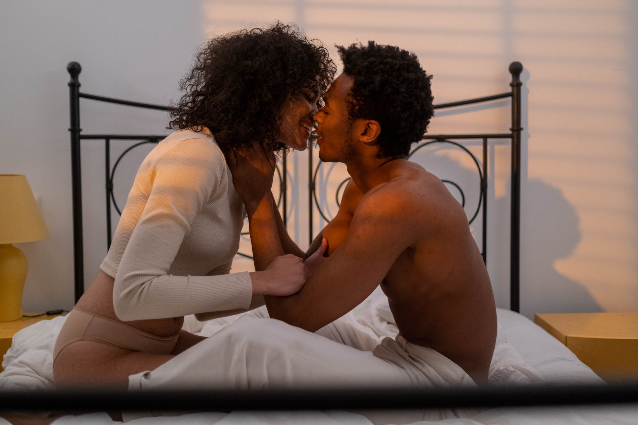 A couple kissing while sitting on the bed