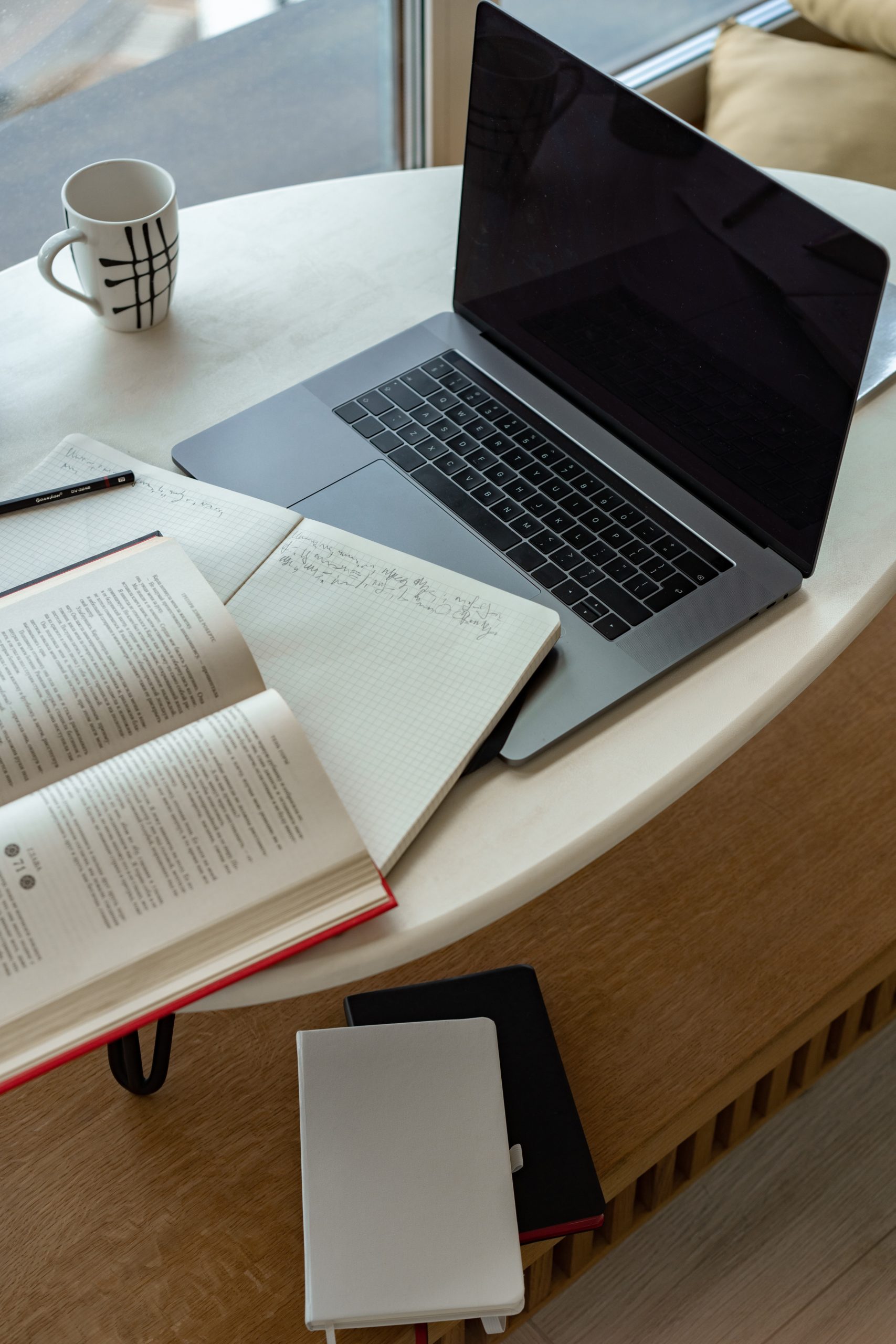 A notebook and laptop sitting on a white table