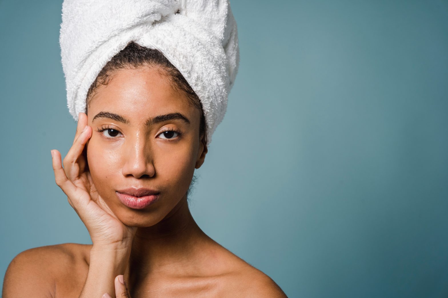 Calm young woman with perfect skin touching face after shower