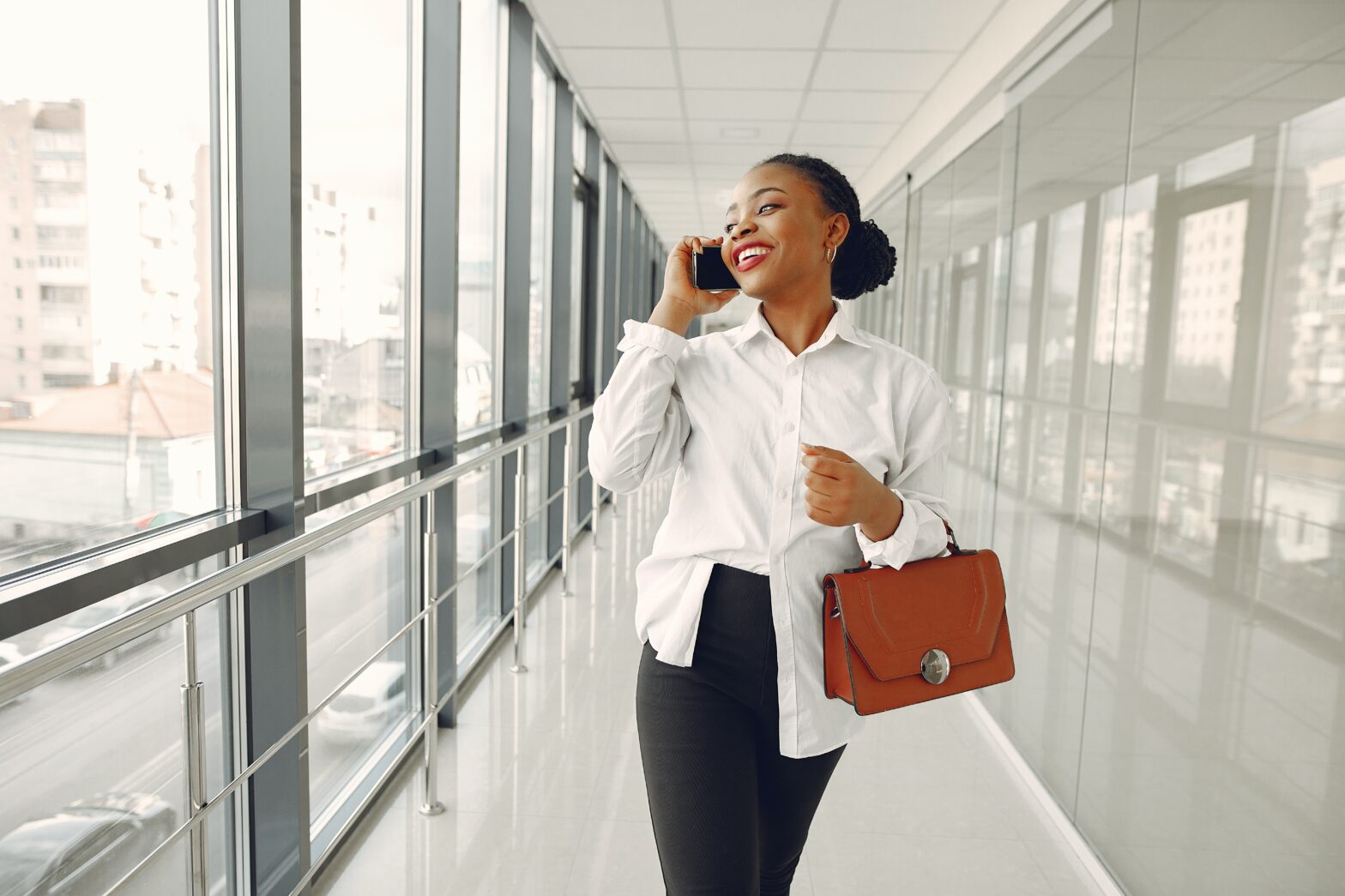 Cheerful woman talking on smartphone in modern office building