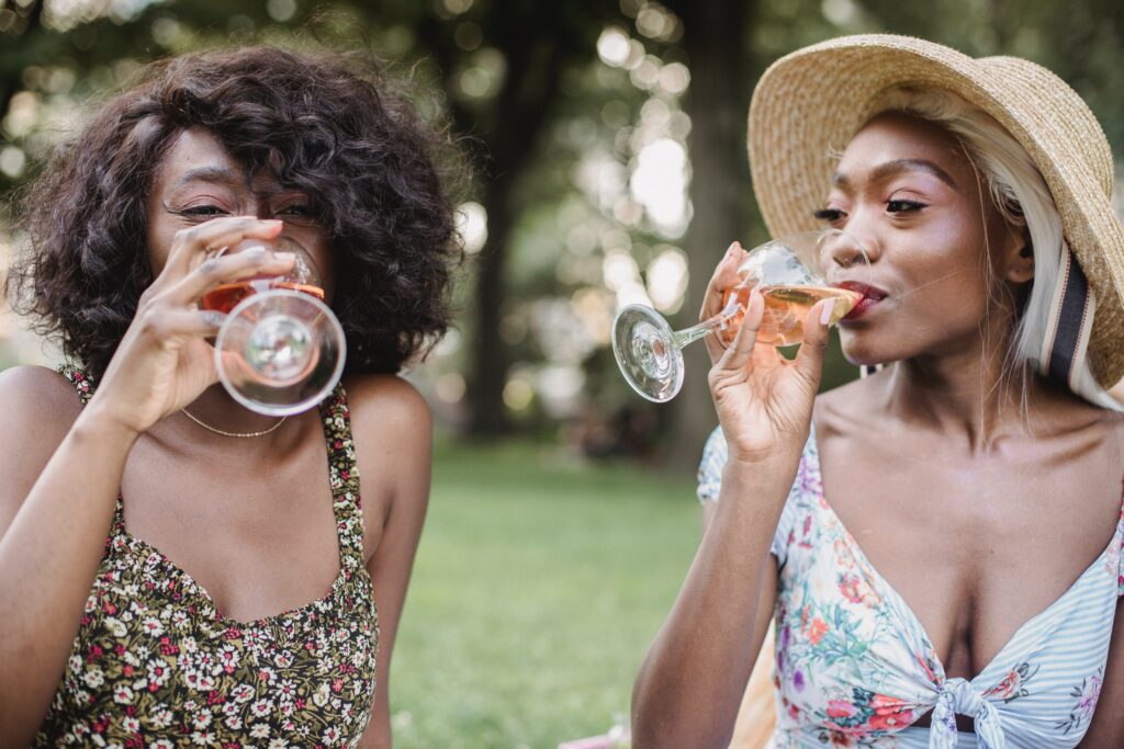 Two women drinking wine from Black-owned wine brands
