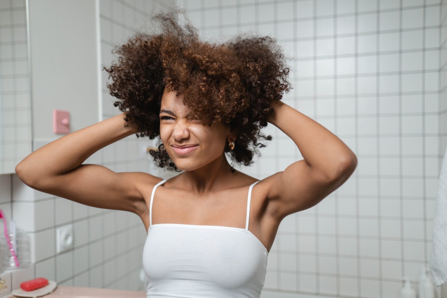 black woman curly hair in bathroom hands in hair