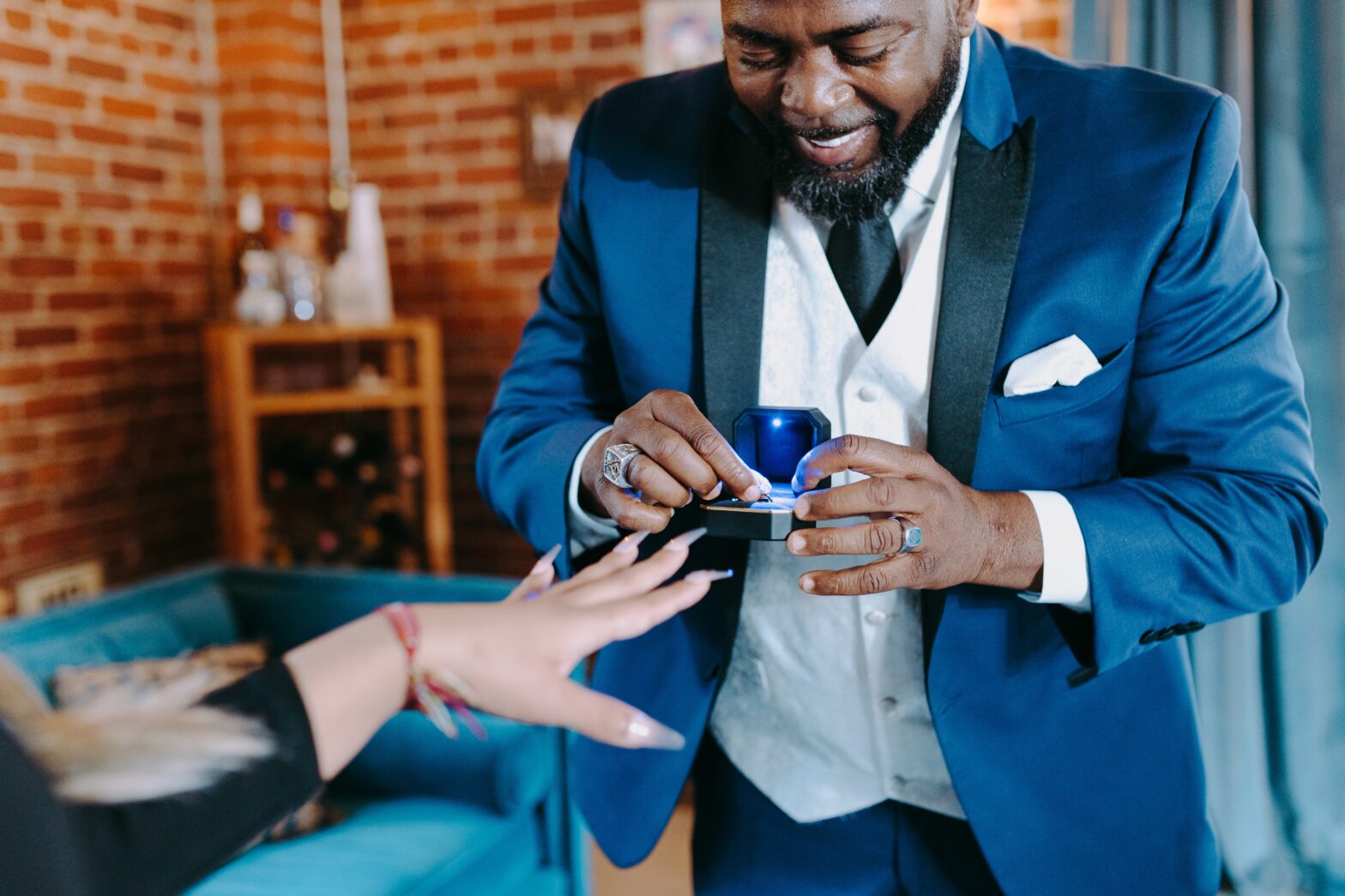 a black man in a suit proposes to a woman with a non traditional engagement ring