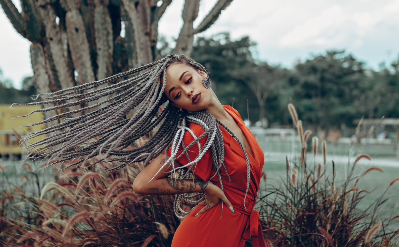 Black woman posing in red jumpsuit with braids outside
