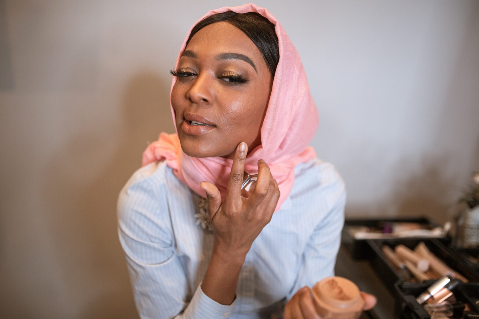 Black-woman-in-white-long-sleeve-shirt-and-pink-applying-make-up