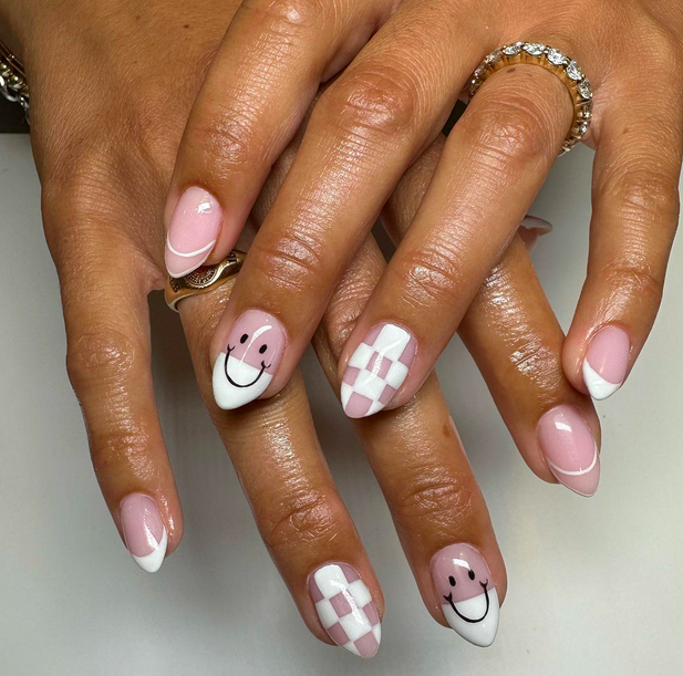 These smiley face nail design ideas are perfect for the fall. Pictured: smiley face nails on two hands clasped one over the other.