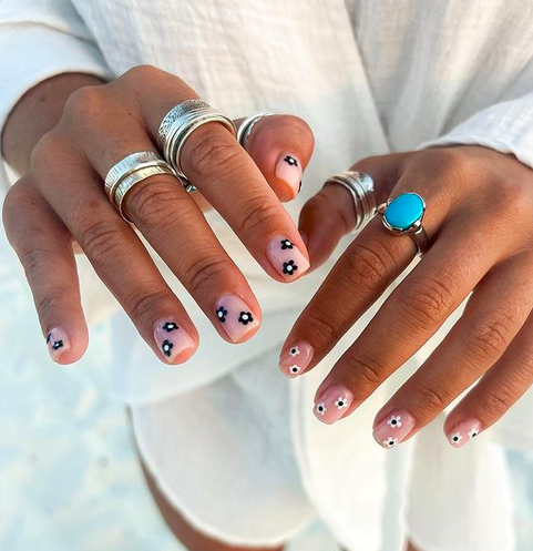Daisy nails are a simple yet great way to decorate your hands. Pictured: two outstretched hands with daisy nail art.