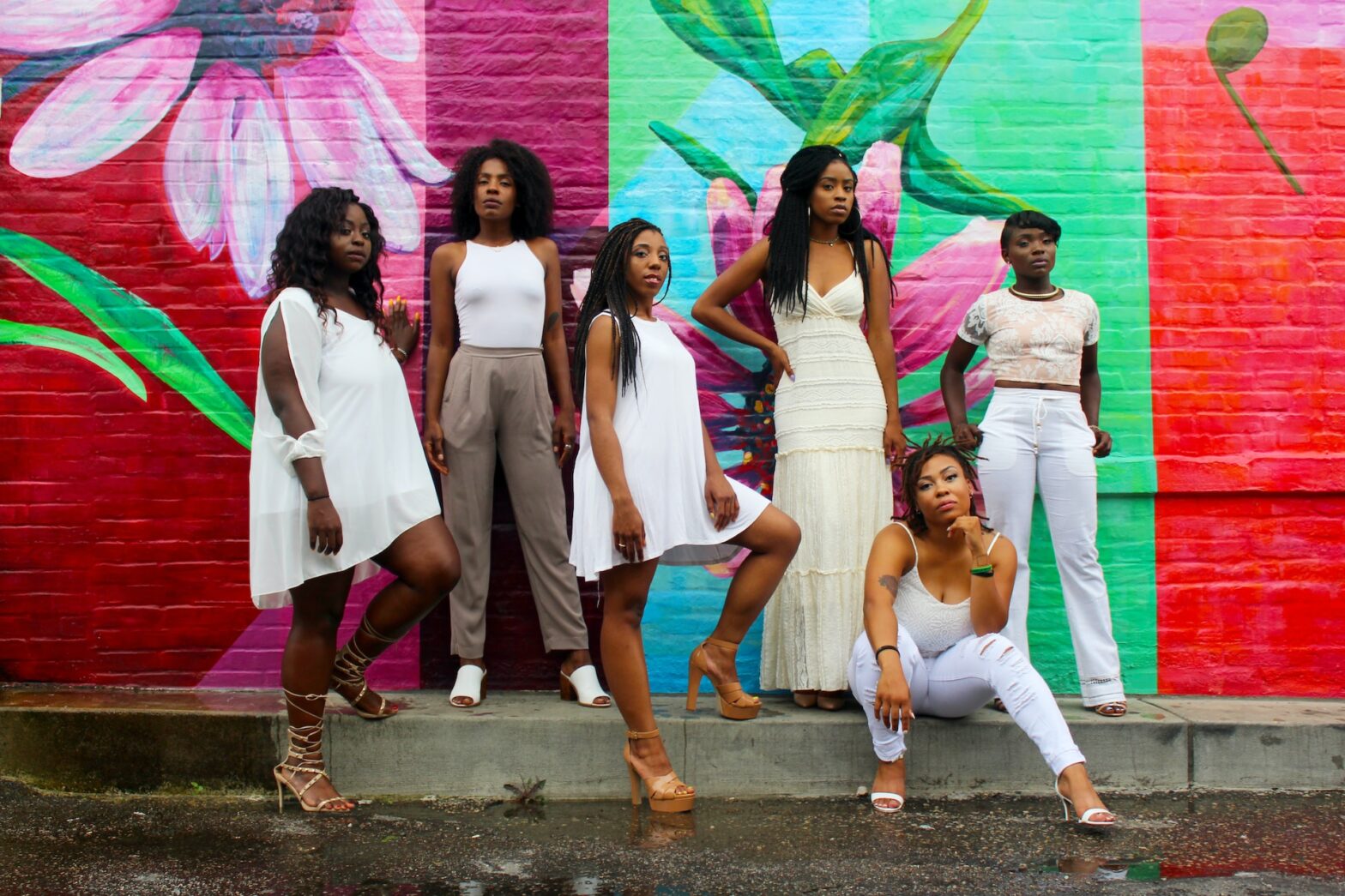 What are some uncommon symptoms of endometriosis? PIctured: a group of black women dressed in white against a colorful wall backdrop.
