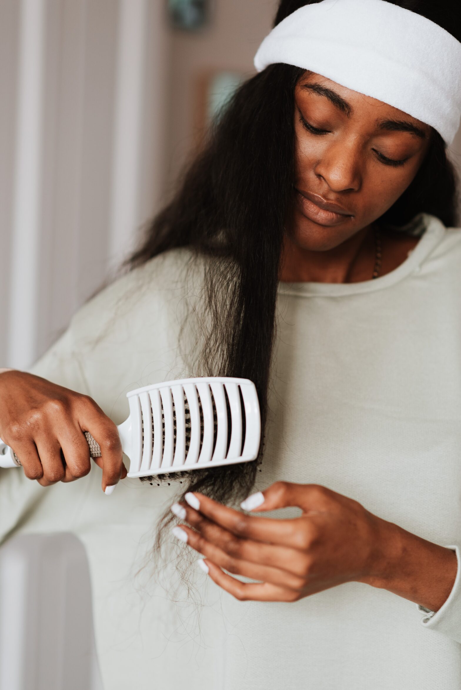 A black woman combing her hair out. Marula oil is a great supplement for hair support.