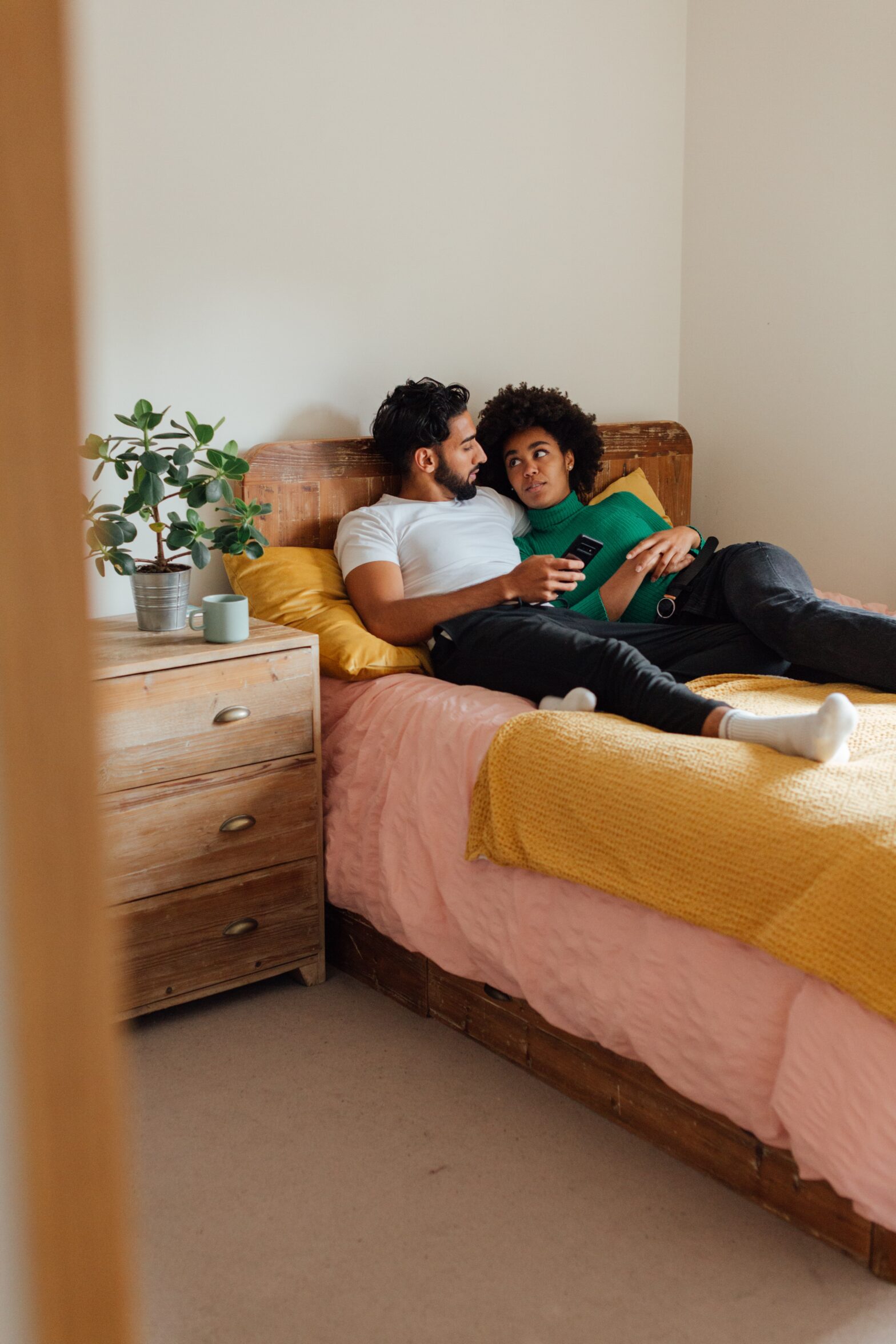 A young black couple lying down on a bed together.