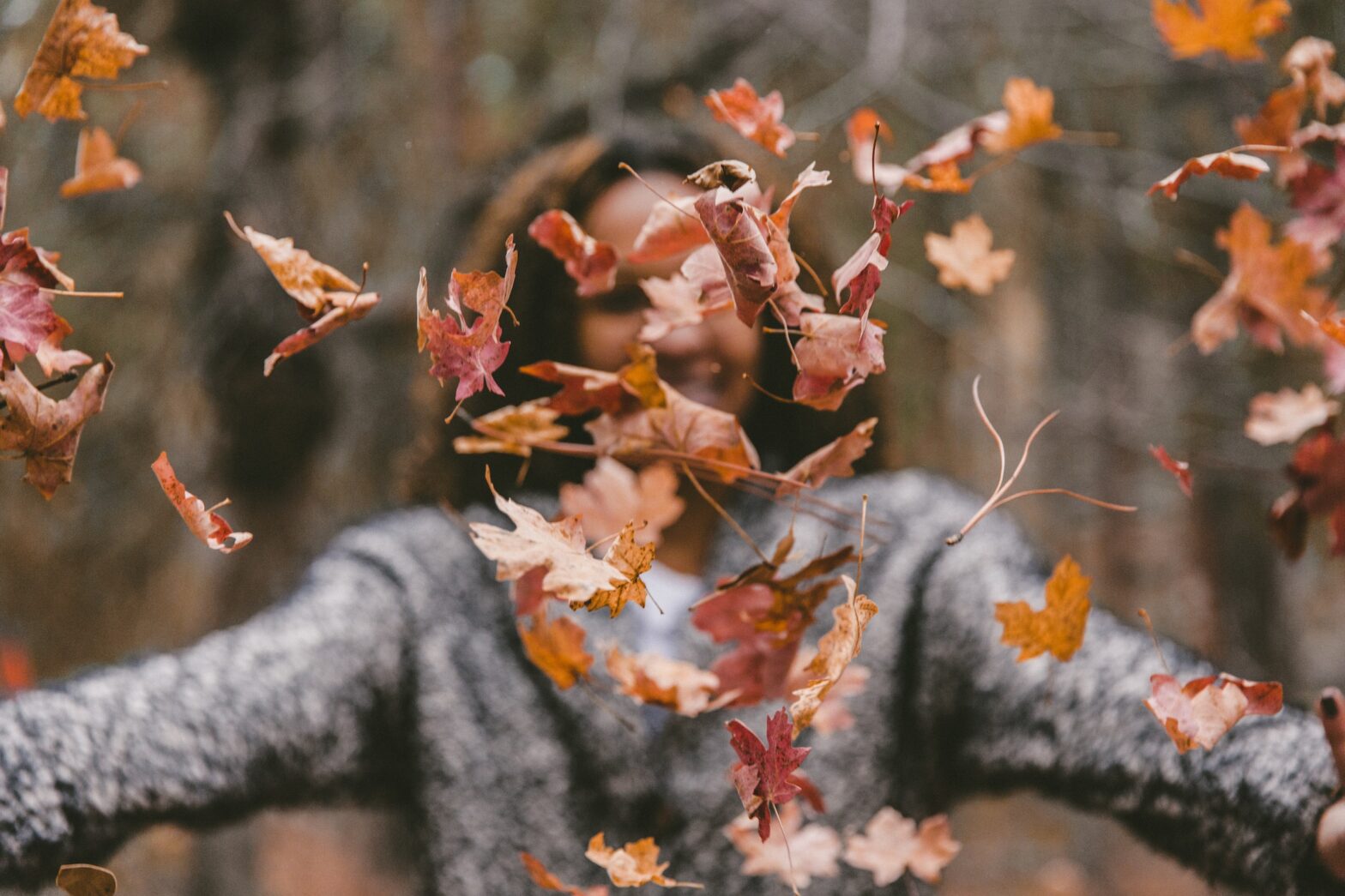 A woman tossing leaves in front of her face