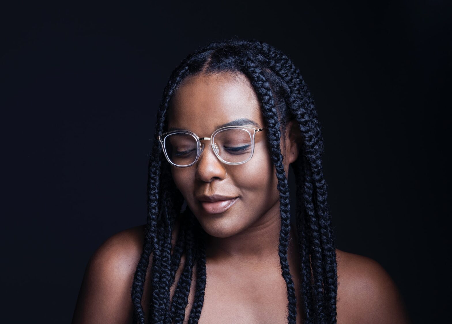 A women with braids and glasses looking down
