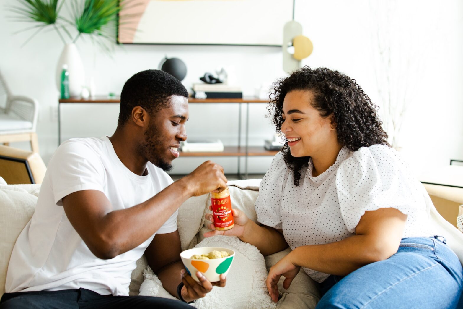 Black couple sitting on couch eating and getting to know each other.