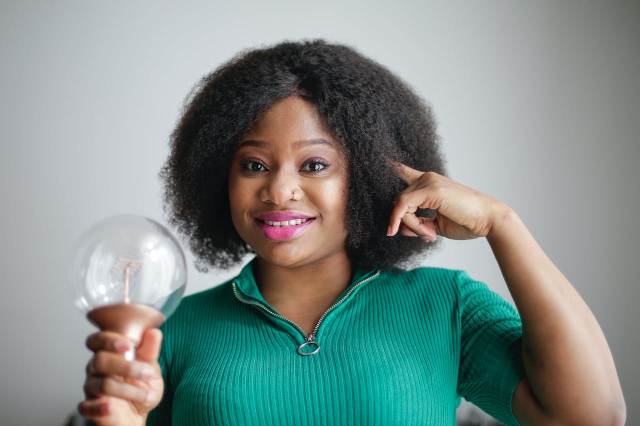 These life hacks are here to make everyday a lot easier. Pictured: a woman smiling while holding a lightbulb and poking her head.