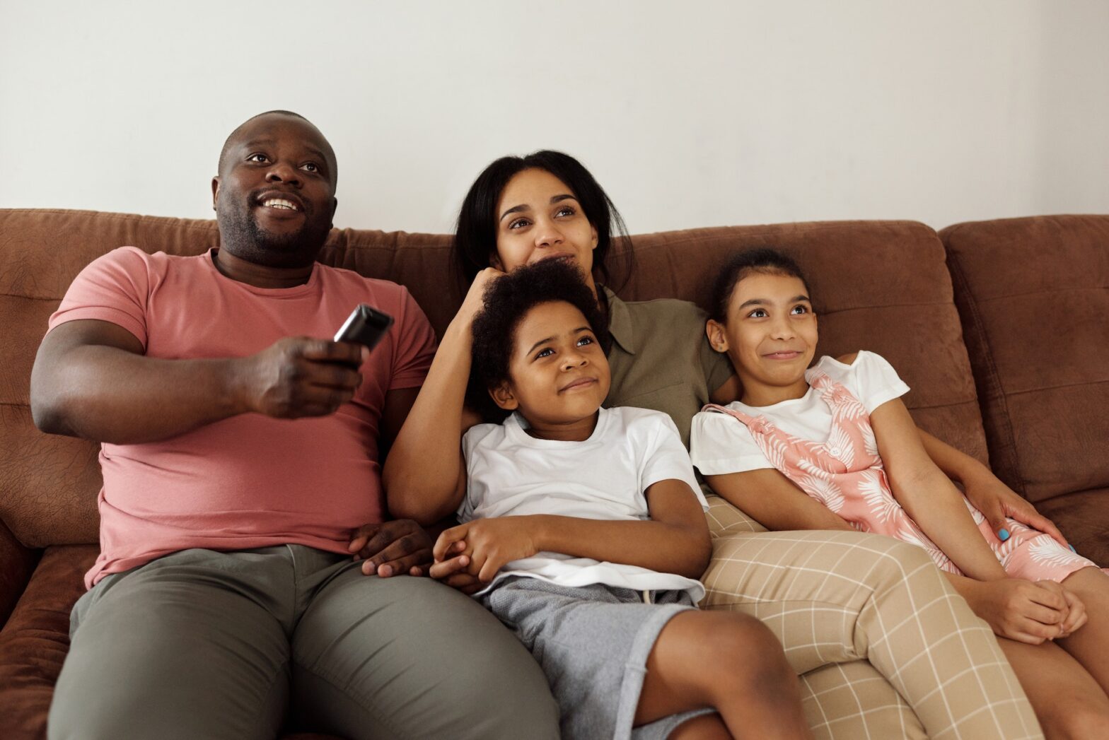 A family sitting on a sofa watching television