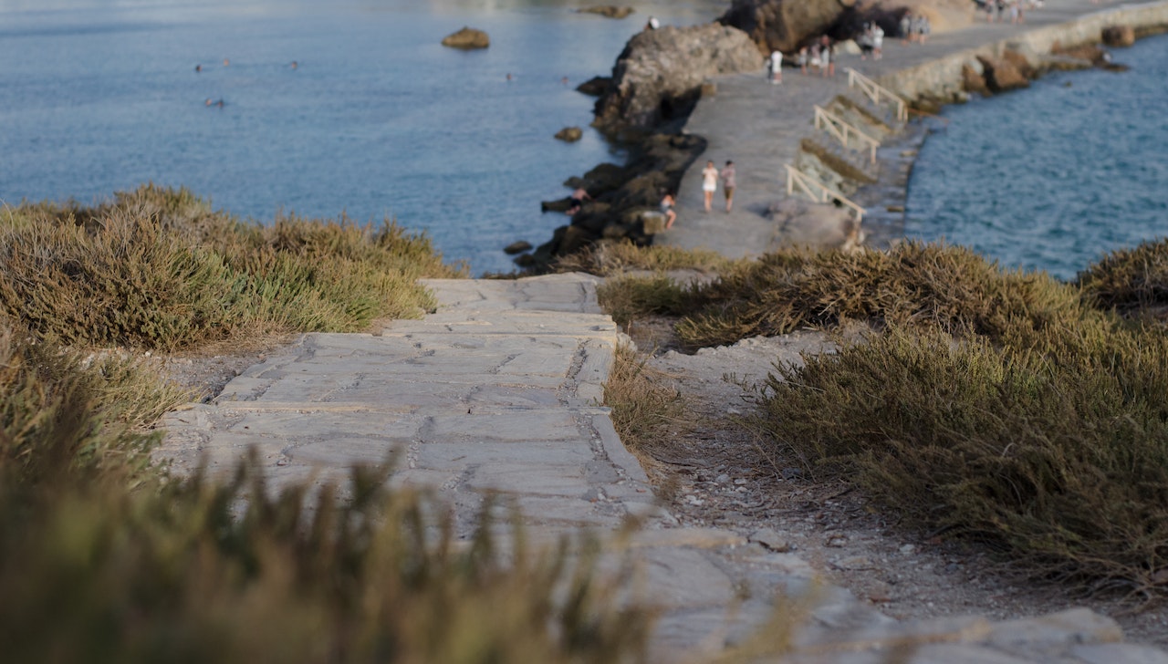Learn about what a Life Path Number is and what it means for you destiny in life. Pictured: People in the distance walking along a rocky path surrounded by water.