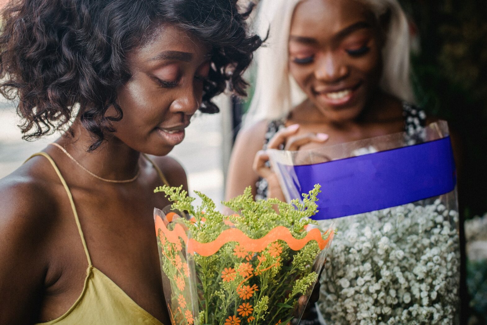 Two black women looking at a bouquet of flowers