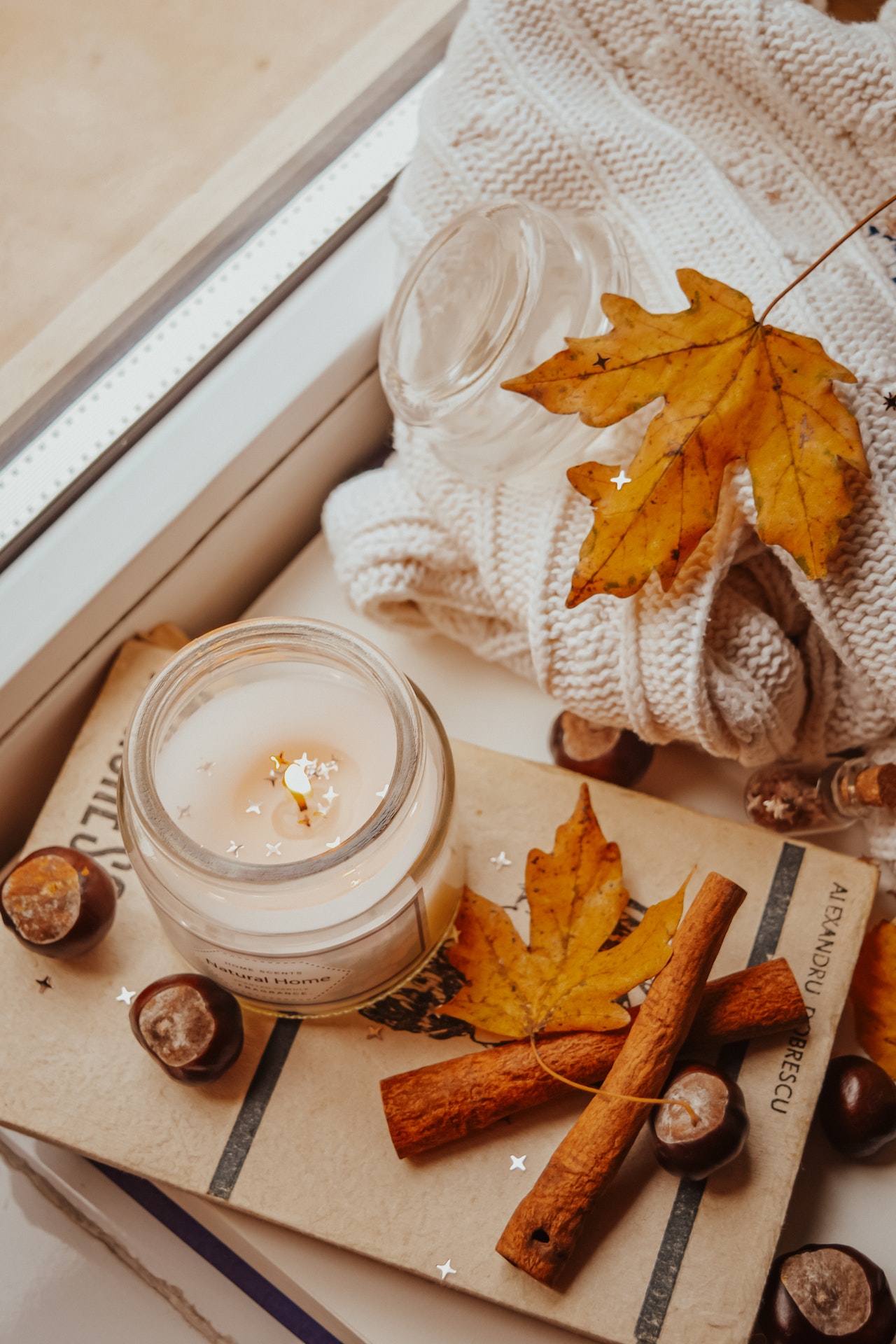 A candle burning by leaves and fall scents