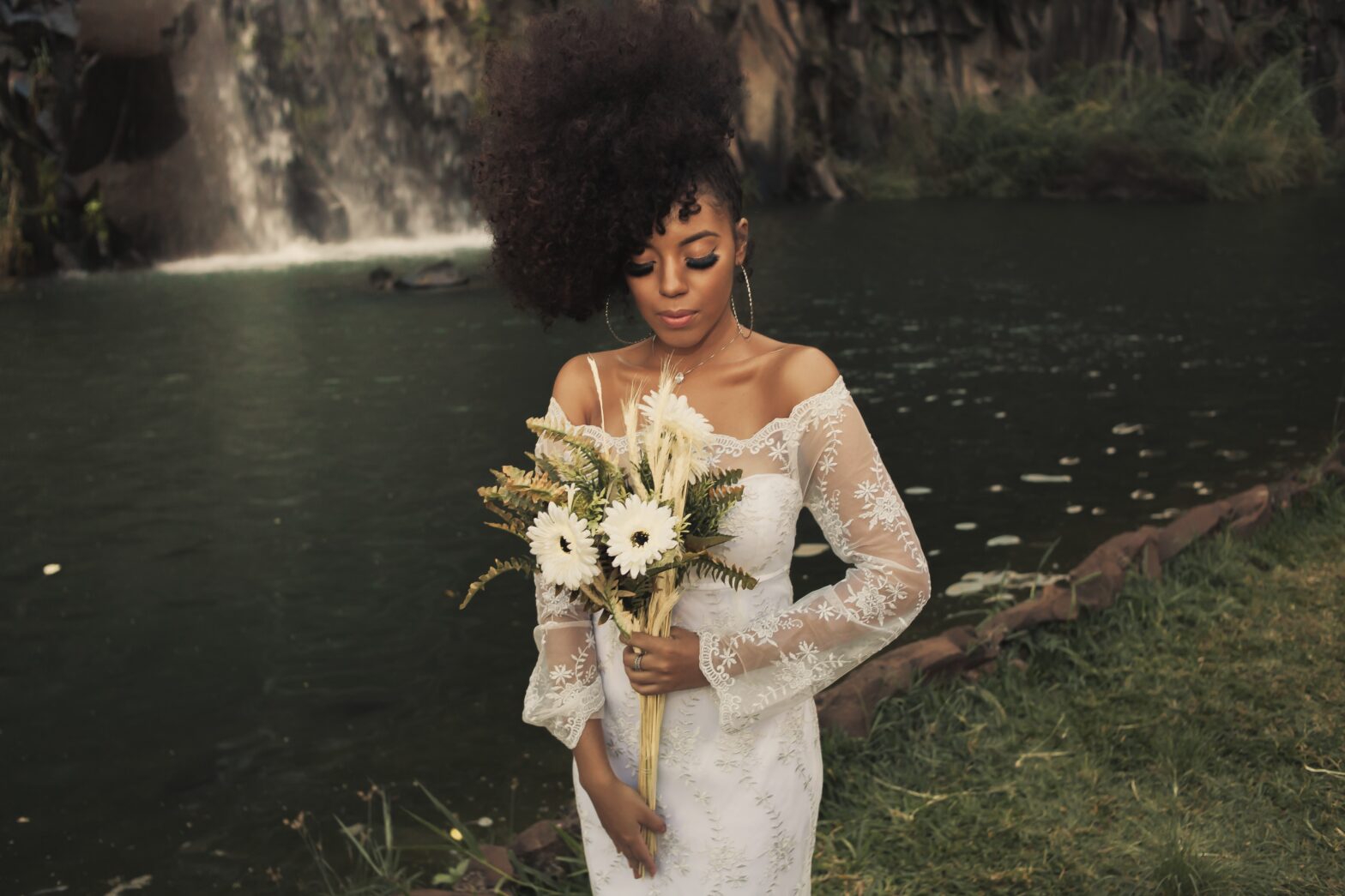 Black-woman-in-white-wedding-dress-holding-flowers-outdoors