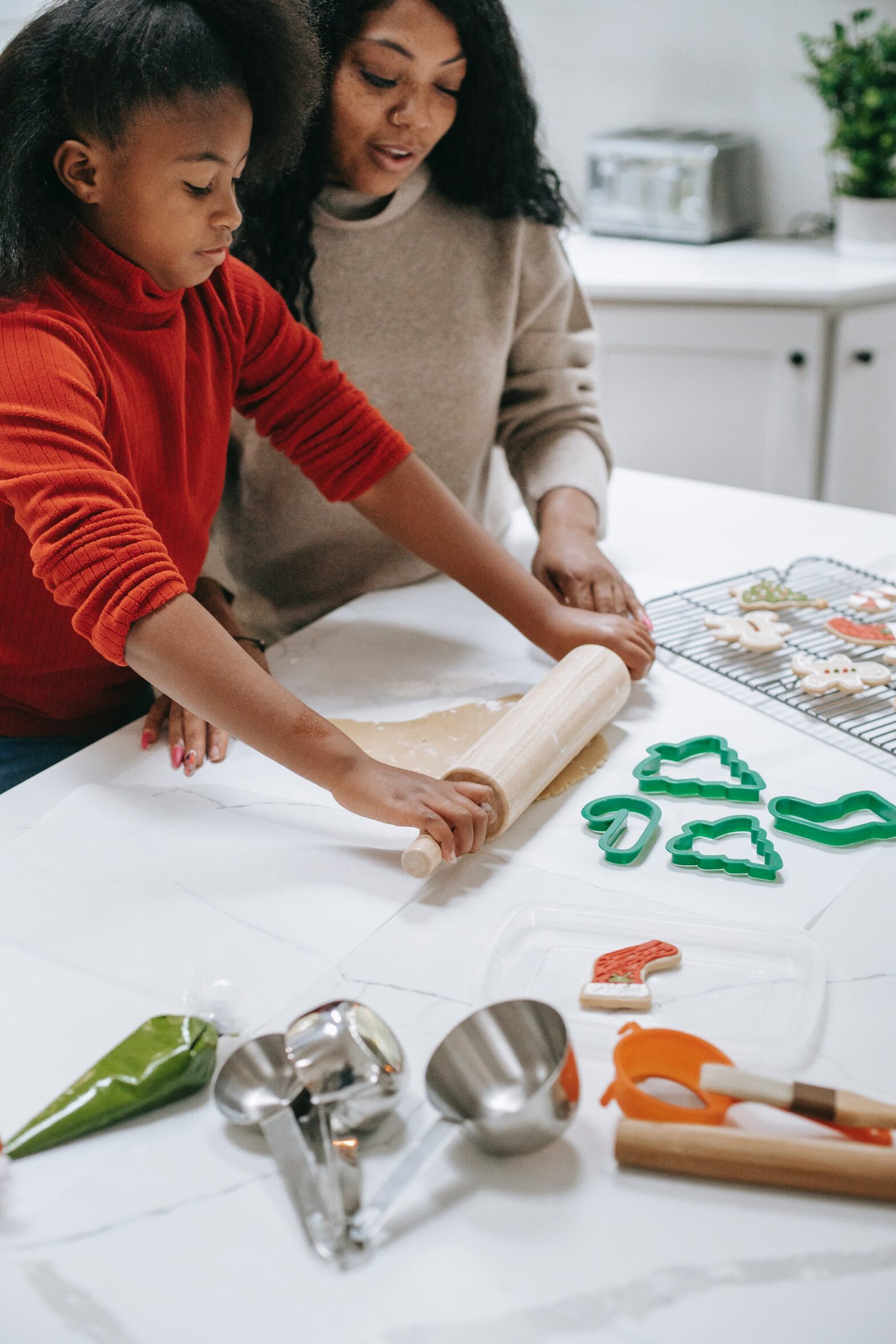 A mom and daughter roll cookies; family time bonding